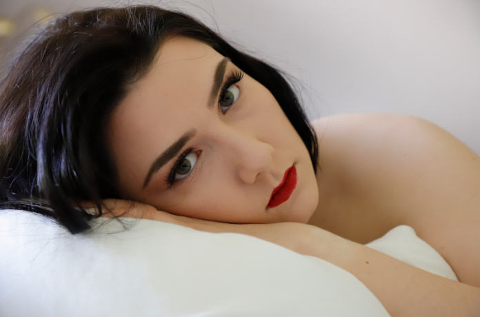 «امرأة مستندة إلى وسادة بنظرة مباشرة وأحمر شفاه