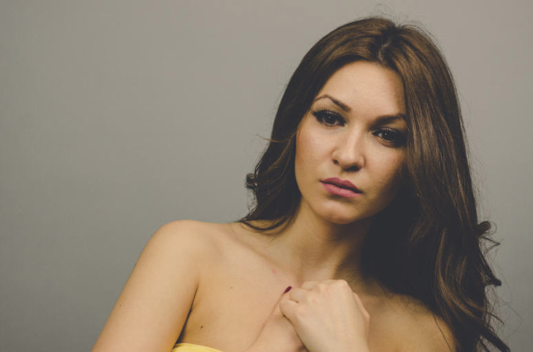 امرأة بشعر بني طويل تنظر بجدية وهي تفكر بصحتها الجنسية ومشاكل العلاقة الحميمة.