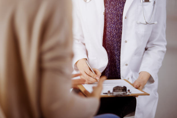 Close-up of a doctor’s hands explaining hormone therapy to a woman, highlighting safety, balance, and well-being during menopause treatment.