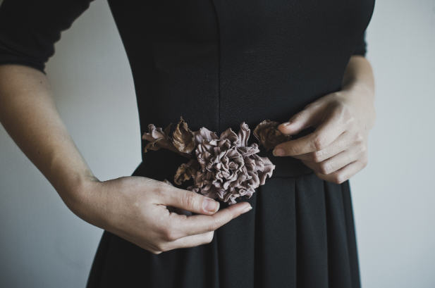 Woman adjusting a floral accessory on her black dress, symbolizing body awareness and hormonal changes.