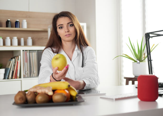 Female nutritionist holding an apple, emphasizing the role of healthy eating in supporting hormonal balance.