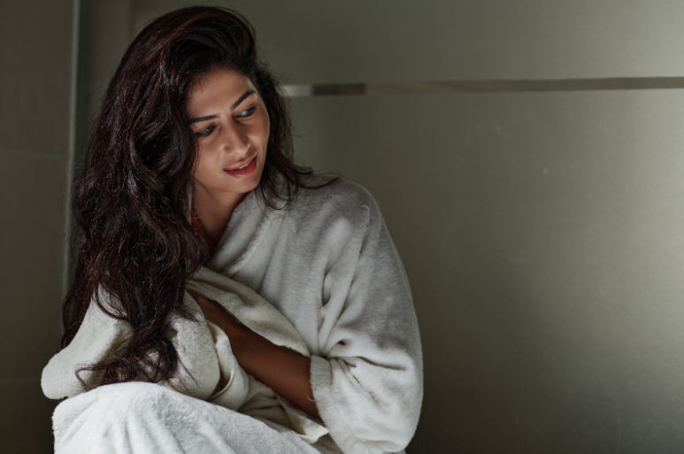 امرأة بالغة تبدو متأملة وهادئة، تضع يدها على بطنها في تعبير عن الوعي بالجسد والانتباه للأعراض الصحية