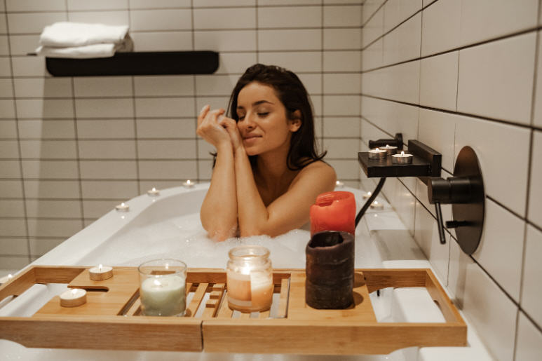 امرأة في حمّام منزلي نظيف مع منتجات عناية شخصية متعددة، في صورة تعبّر عن الإفراط في النظافة وتأثيره على الجلد الحساس